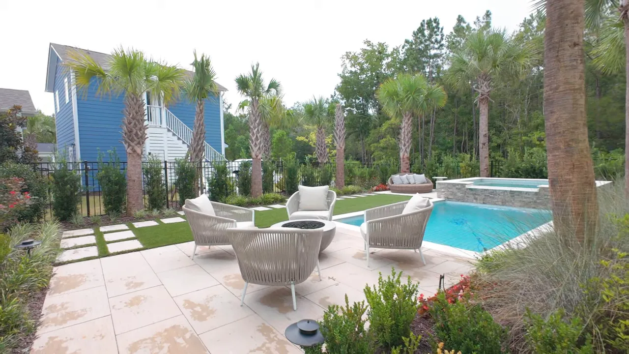Backyard patio with turquoise pool white lounge chairs and tropical landscaping