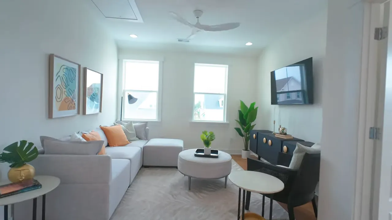 Upstairs loft with white seating black chairs and wall mounted television