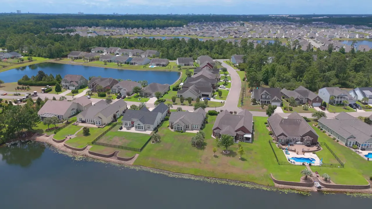 Aerial drone view of a neighborhood with single-family homes, yards and small lakes.