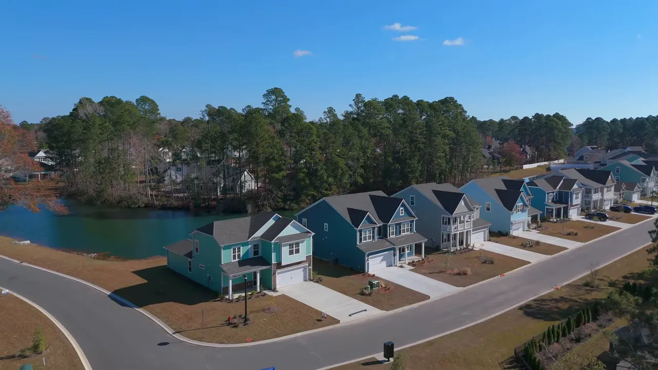 Aerial shot of a new construction neighborhood showing rows of single-family homes, streets and a small pond