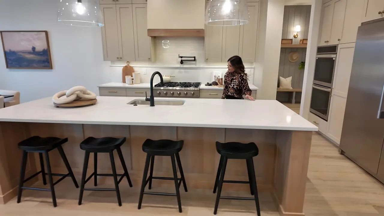 Kitchen island with bar stools, quartz countertop, and built-in range in new construction home