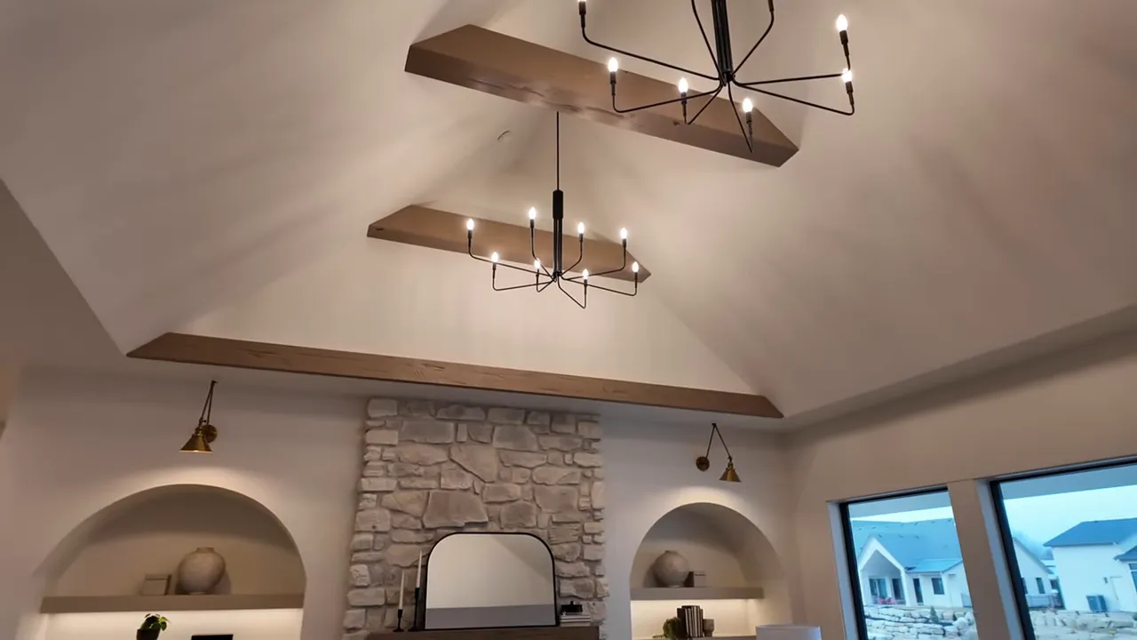 High ceiling with statement lighting above stone fireplace wall