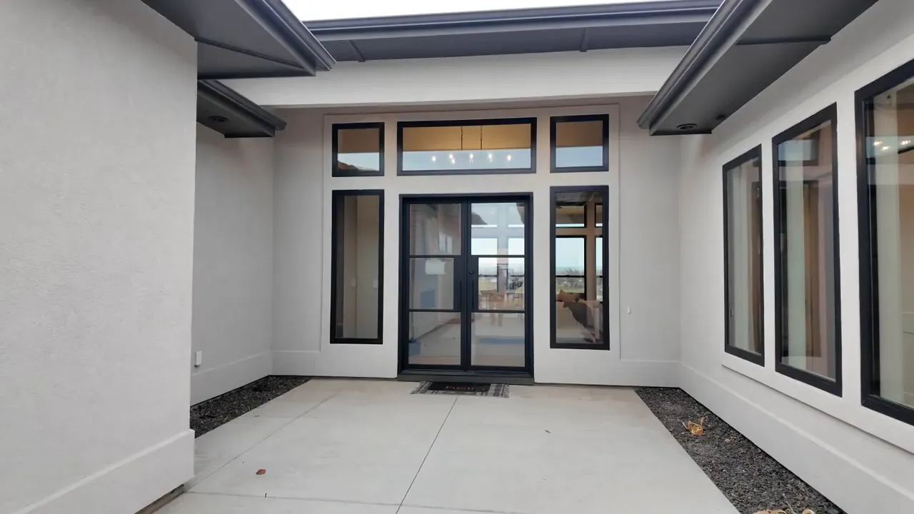 Covered courtyard entrance with black framed glass door and windows