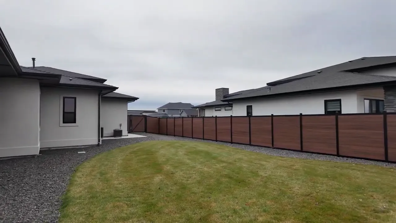 Wide grassy backyard bordered by landscaping and privacy fence