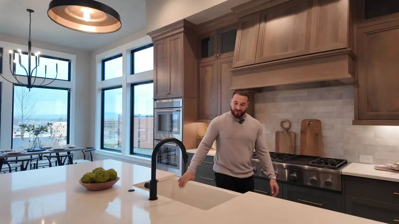 Large quartz kitchen island with black faucet and wood cabinetry