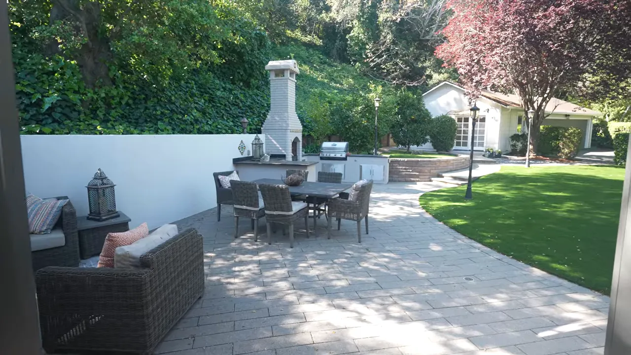 Patio with outdoor dining area fireplace lawn and detached structure in background