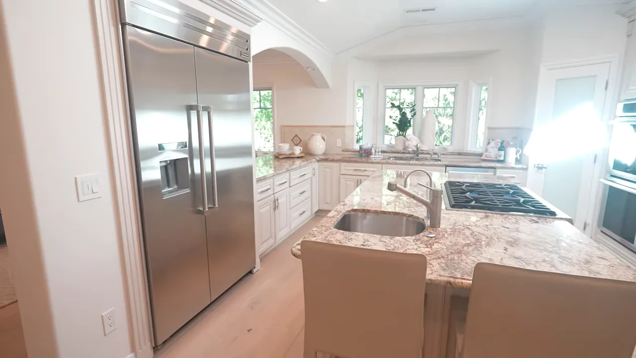 Bright kitchen with large island built in refrigerator sink and double ovens
