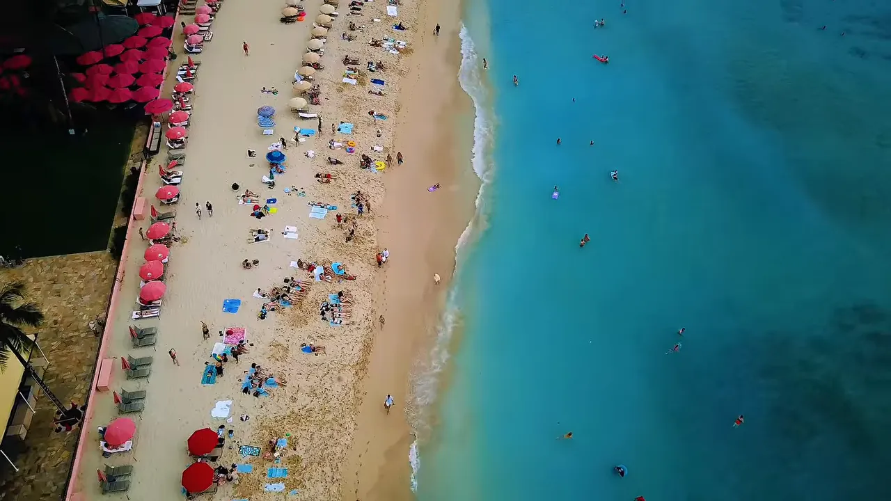 Aerial view of crowded beach with umbrellas and swimmers