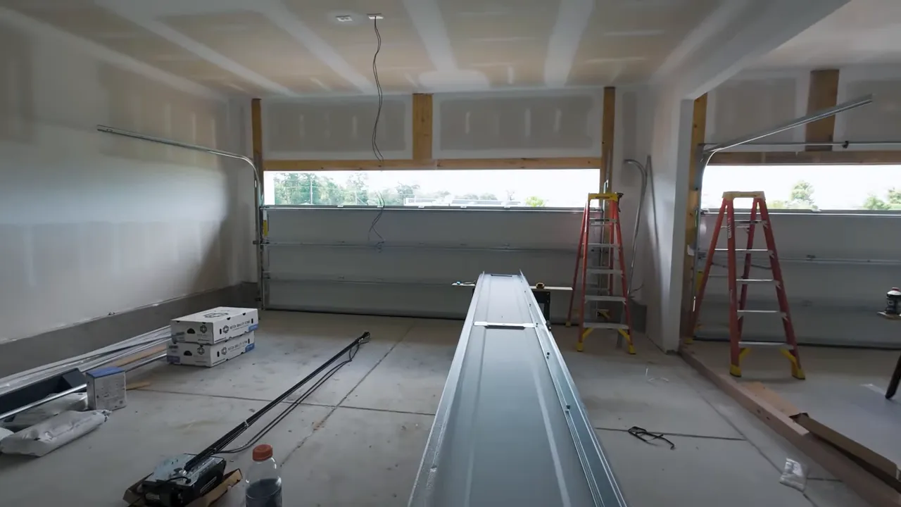 Wide three-car garage under construction with ladders, tools, and three separate garage door bays