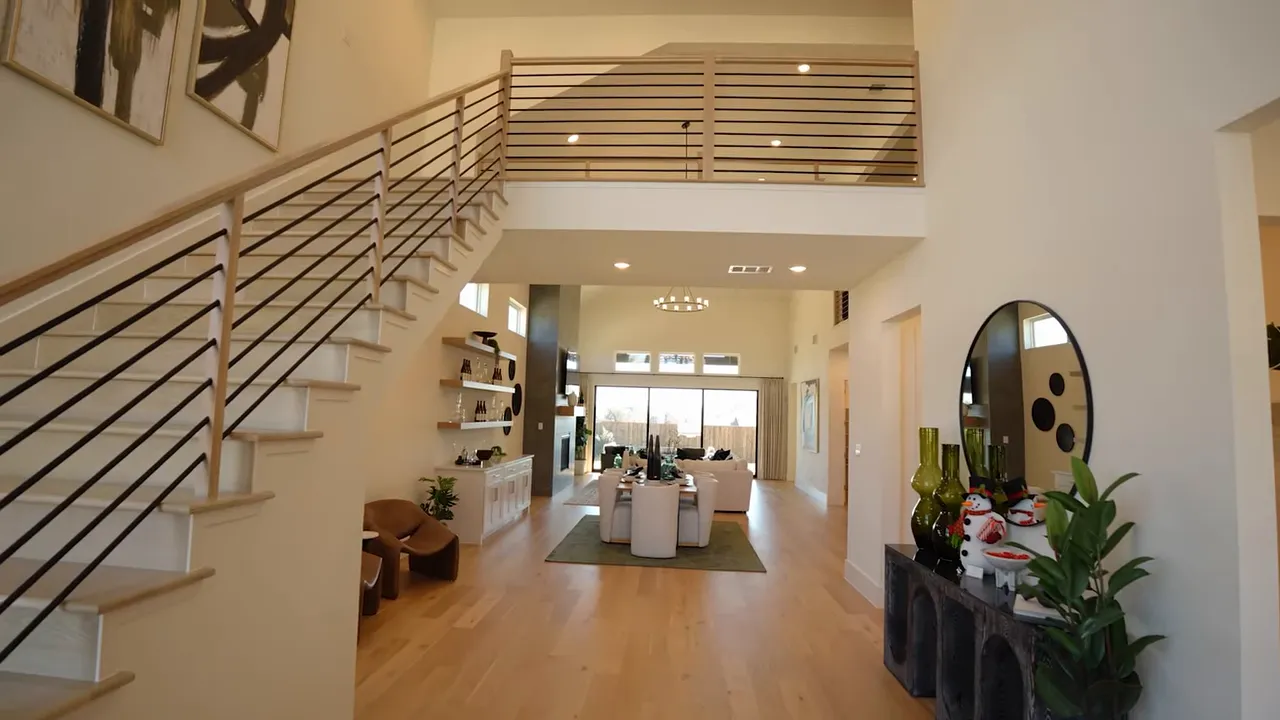 Wide view of two-story foyer with staircase on left and open living room leading to slider