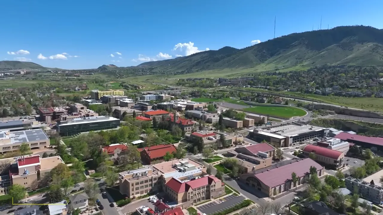Wide aerial view of Golden, Colorado showing neighborhoods, hills, and nearby mountain landscape