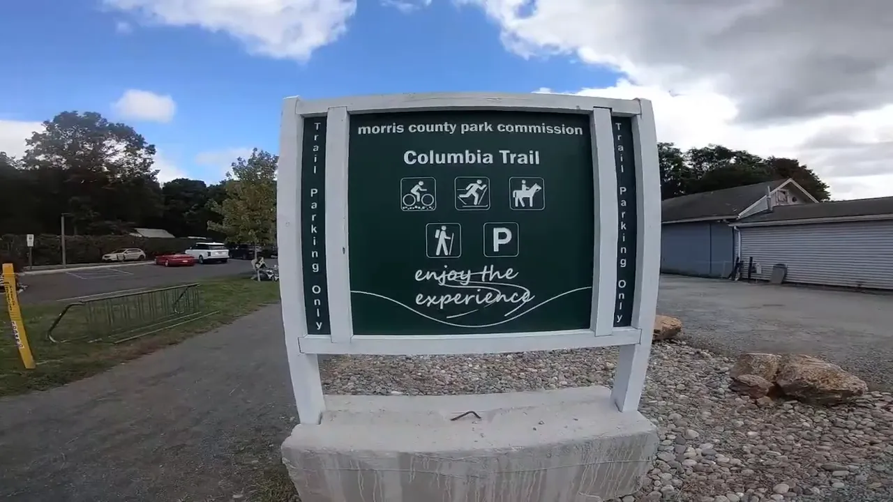 Green sign for Columbia Trail with walking and biking symbols