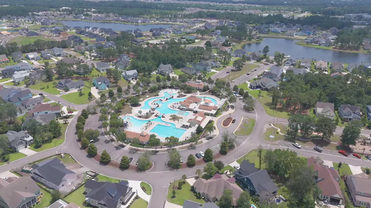 Aerial view of a large resort-style amenity center with multiple pools, swim-up areas, and surrounding homes at Waterbridge