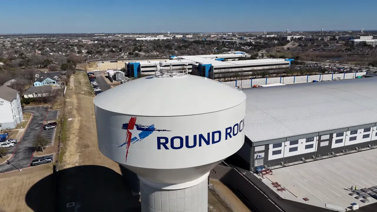 Aerial view of a Round Rock facility with a large “ROUND ROCK” logo on a cylindrical building