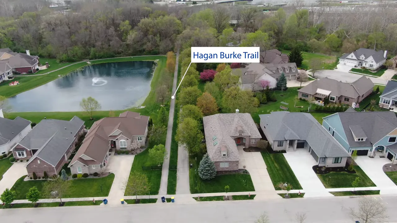 Aerial view of homes, pond, and straight green corridor labeled Hagan Burke Trail