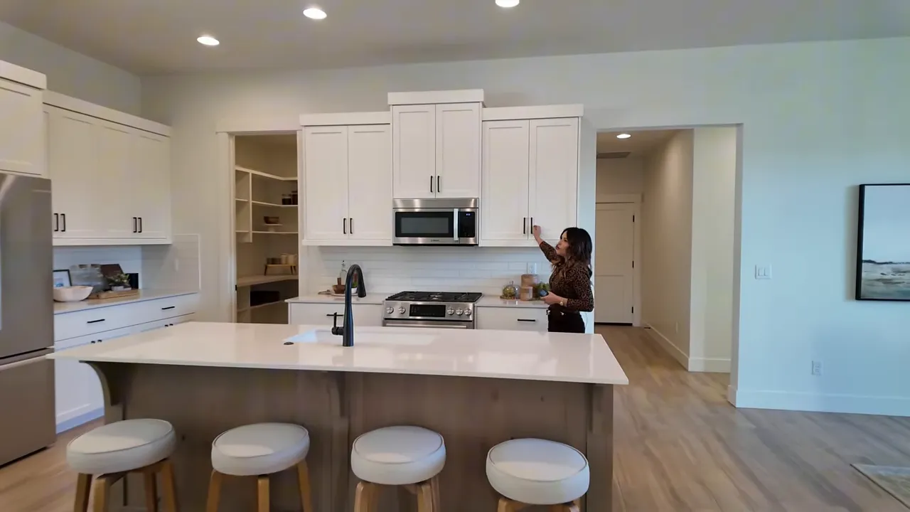 Kitchen island view with seating and white cabinetry in Valnova subdivision home