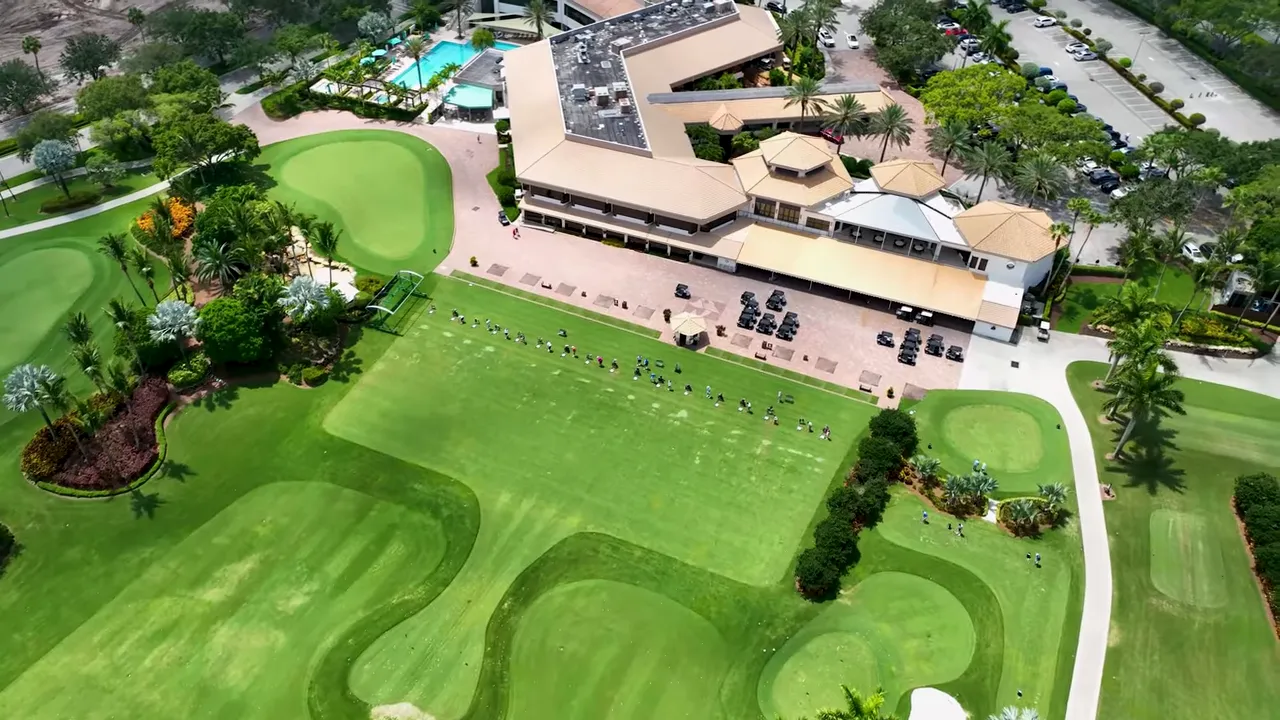 Top-down aerial of a country club showing the clubhouse building, adjacent driving range, practice greens and pool area