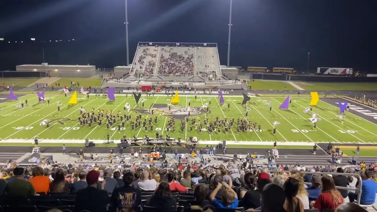 Crowded football stadium with performers on field at night