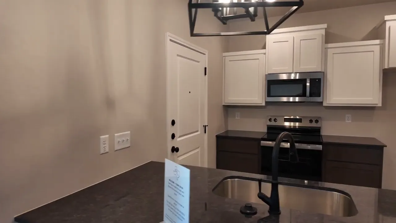 Kitchen walkthrough at 110 Leon Drive duplex with white cabinets, stainless appliances, and dark countertops