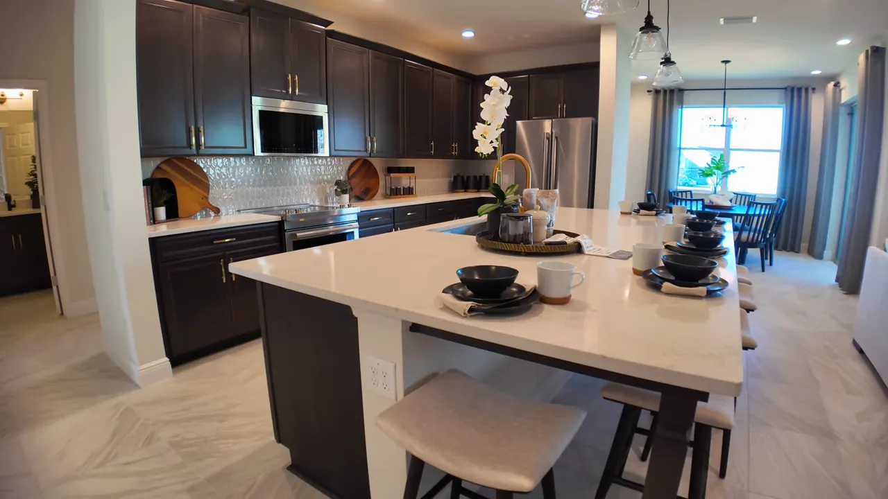 Large kitchen island with seating and a staged dining area in a new home