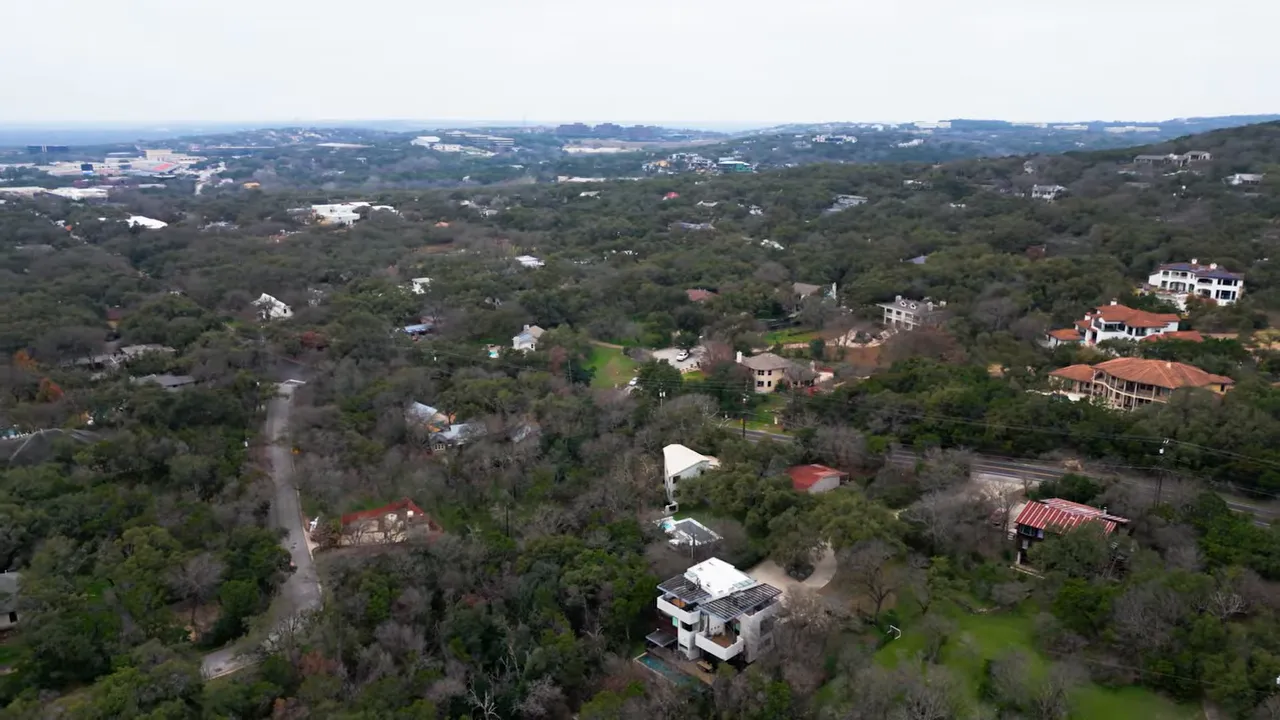 Aerial view of Austin-area suburban neighborhoods with homes, trees, and distant commercial areas
