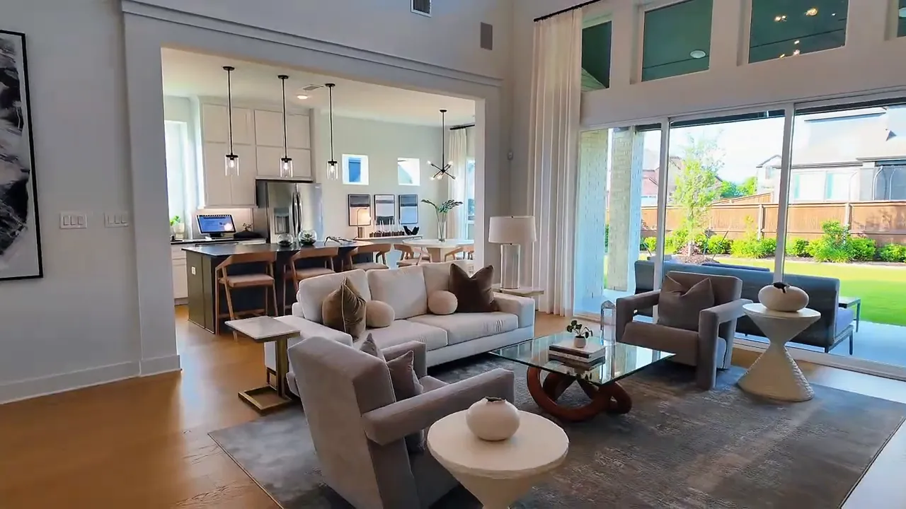 Wide view of open living room with high ceilings and sliding glass doors leading to the backyard patio in a Forney TX new construction home