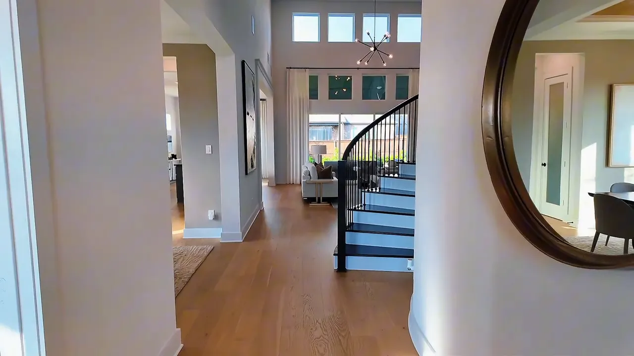 First-floor entry hallway with curved staircase and arched mirror in a Forney TX new construction home