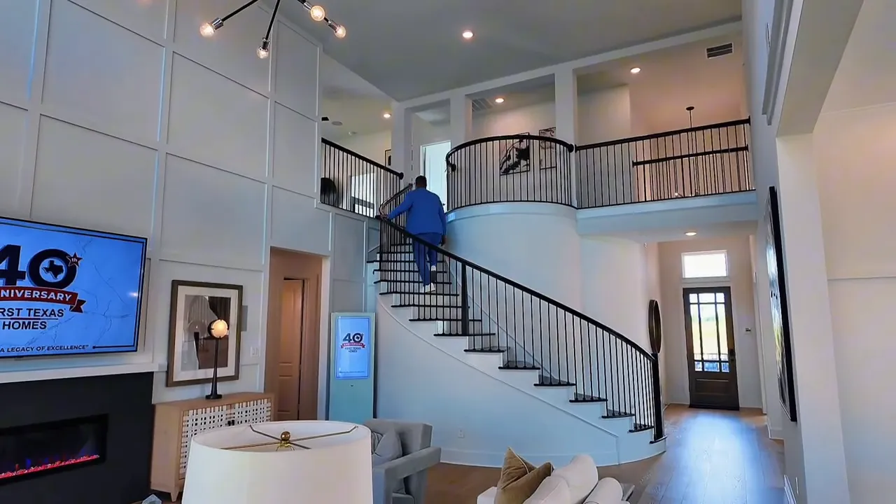 Curved staircase landing and railings inside a Forney TX new construction home with vaulted second-floor view