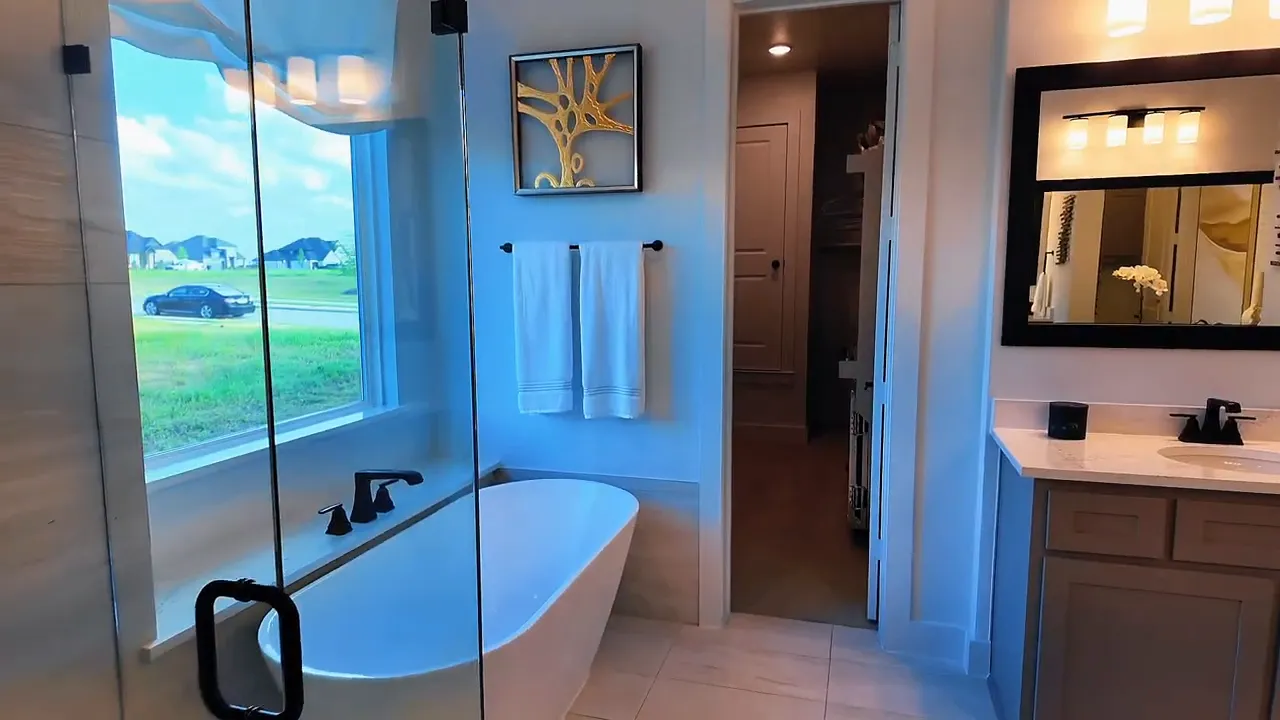 Forney TX new construction primary bathroom with freestanding tub, large window, and dual-sink vanity