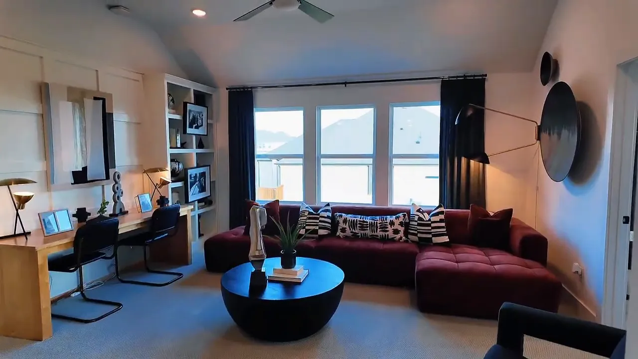 Staged upstairs living room with sofa, coffee table, and large windows in a Forney TX new construction home