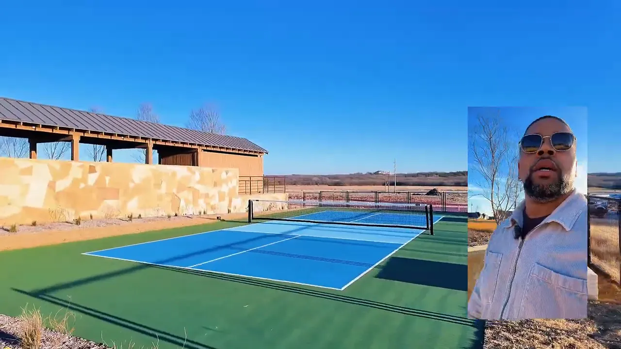 Blue and green pickleball court beside stone wall