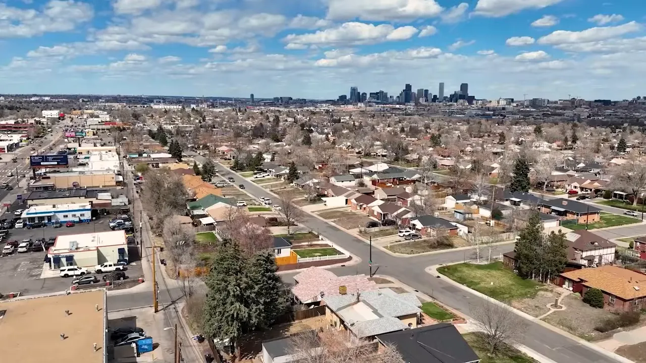 Aerial view of Denver suburb homes and streets with downtown skyline in the distance