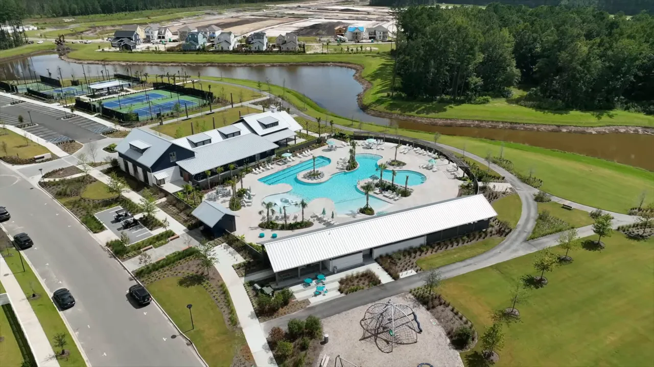 Aerial view of a neighborhood clubhouse with pool, tennis courts, parking and surrounding homes in Summerville SC.