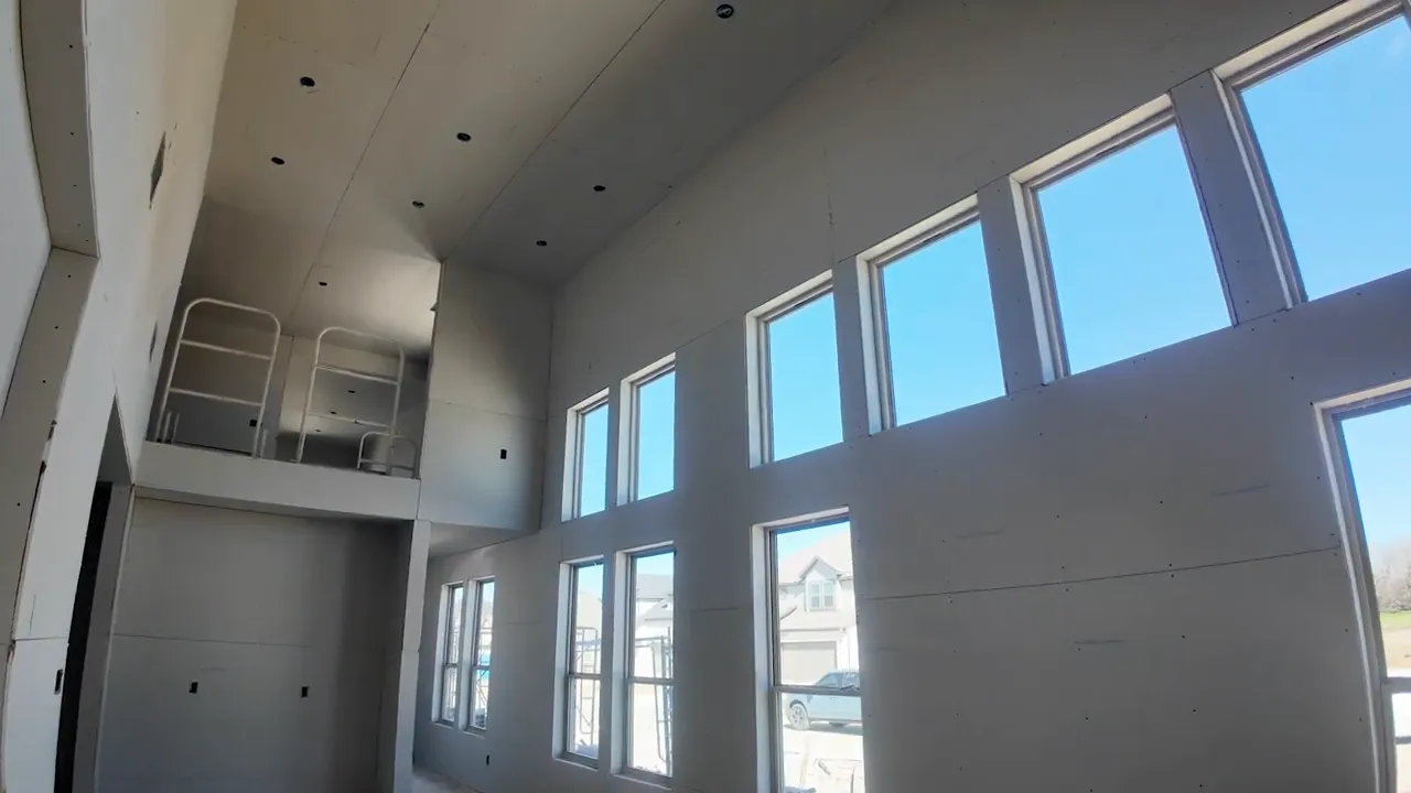 Tall two story living room with multiple windows and an upstairs loft railing