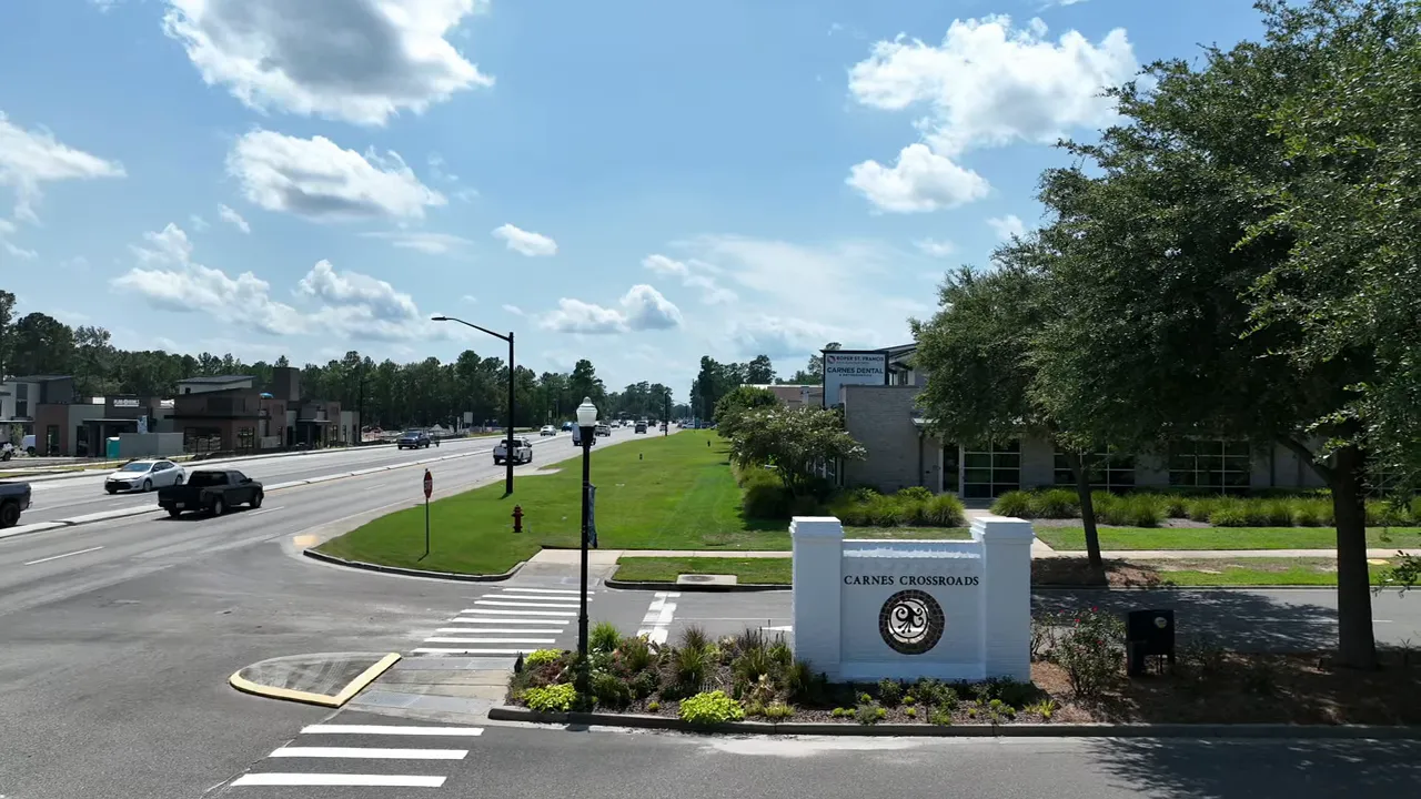 Carnes Crossroads entrance sign with the main thoroughfare and businesses in the background.