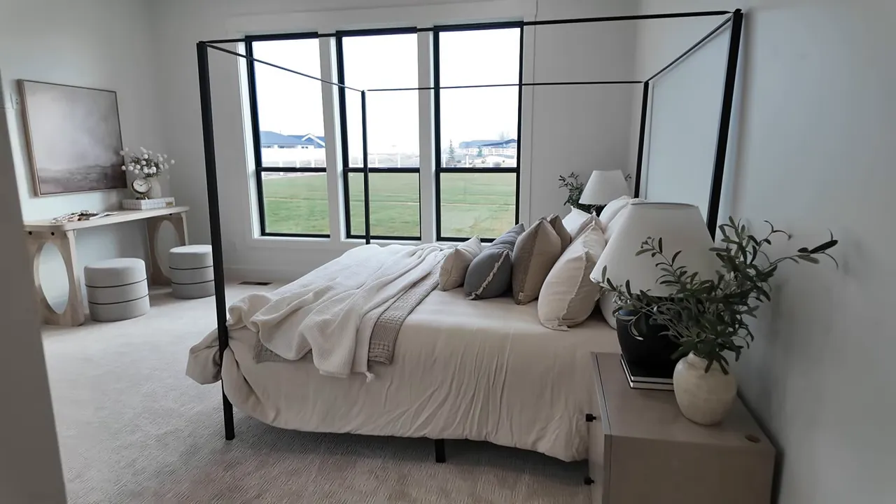 Primary bedroom with bed and large windows overlooking open green space in Middleton Idaho new construction home