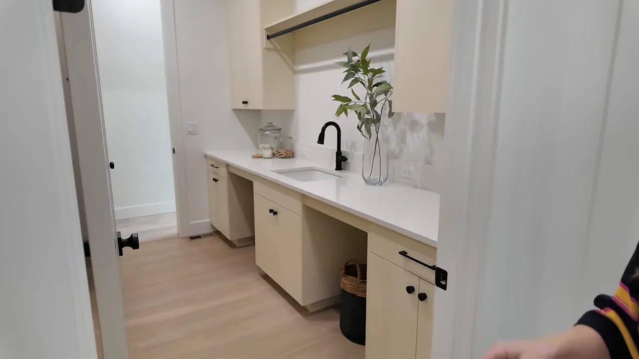 White farmhouse-style wet bar with black faucet and glass shelves in a new construction home