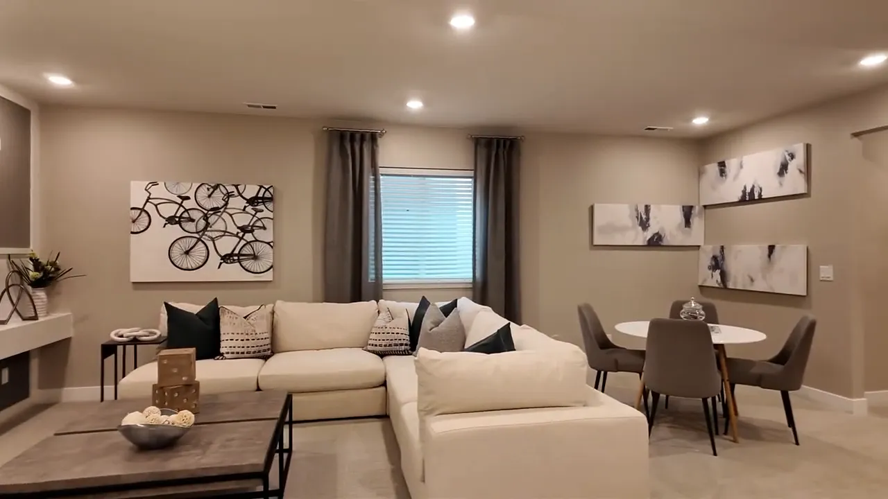 Finished basement recreation room with sectional sofa and dining table in Painted Prairie Residence 2 model home