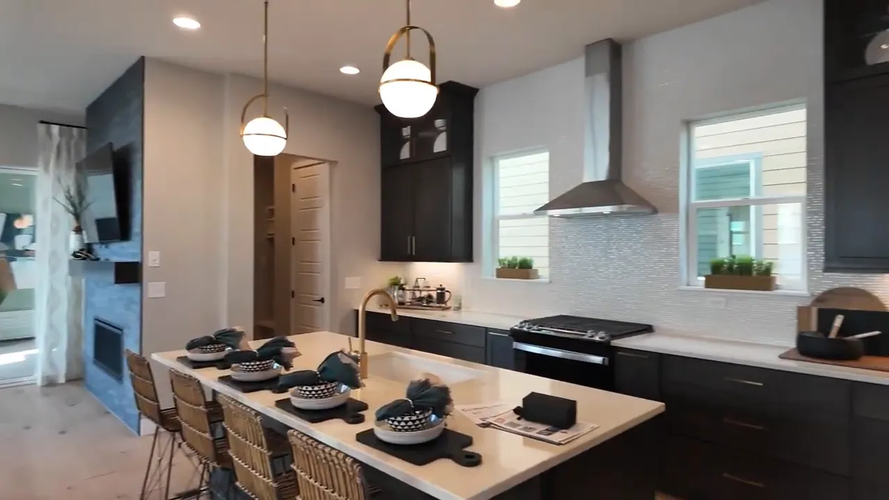 Residence 3 kitchen in Painted Prairie model home with dark cabinets and light backsplash