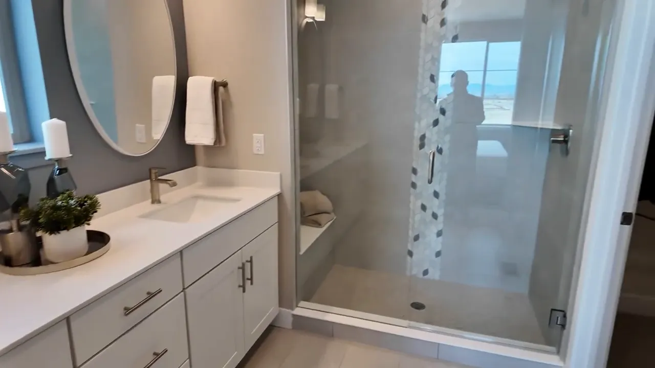 Modern primary bathroom walk-in shower and double vanity in Painted Prairie Residence 2 model home