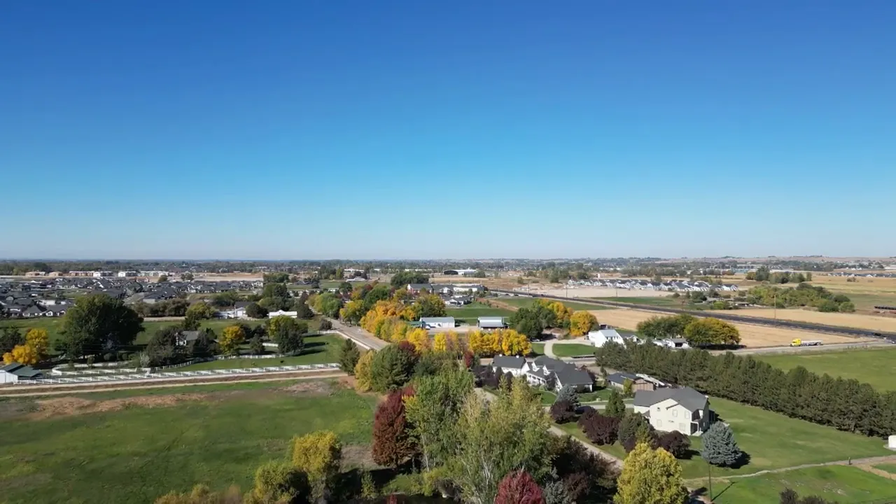 aerial view of suburban neighborhoods with tree lined streets and open land beyond