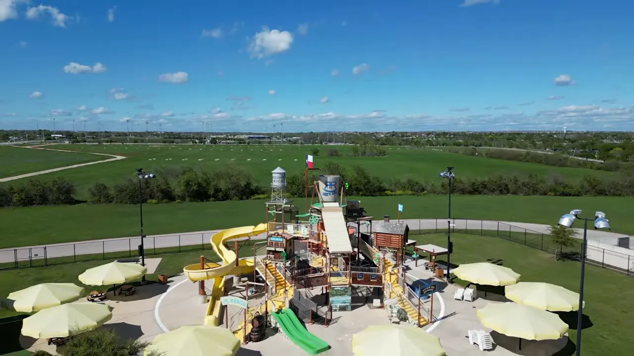 Aerial view of a Round Rock TX playground and community park with green space in the background