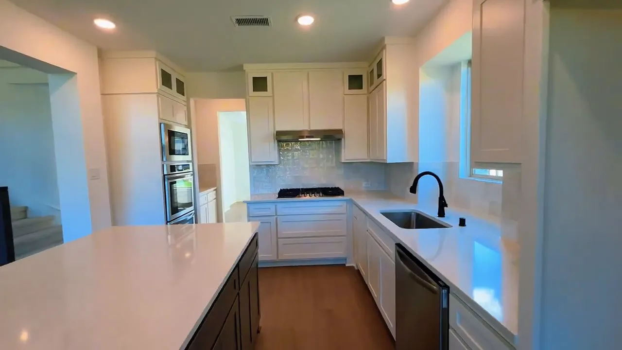 Kitchen with large island white cabinets built in oven and sink under window