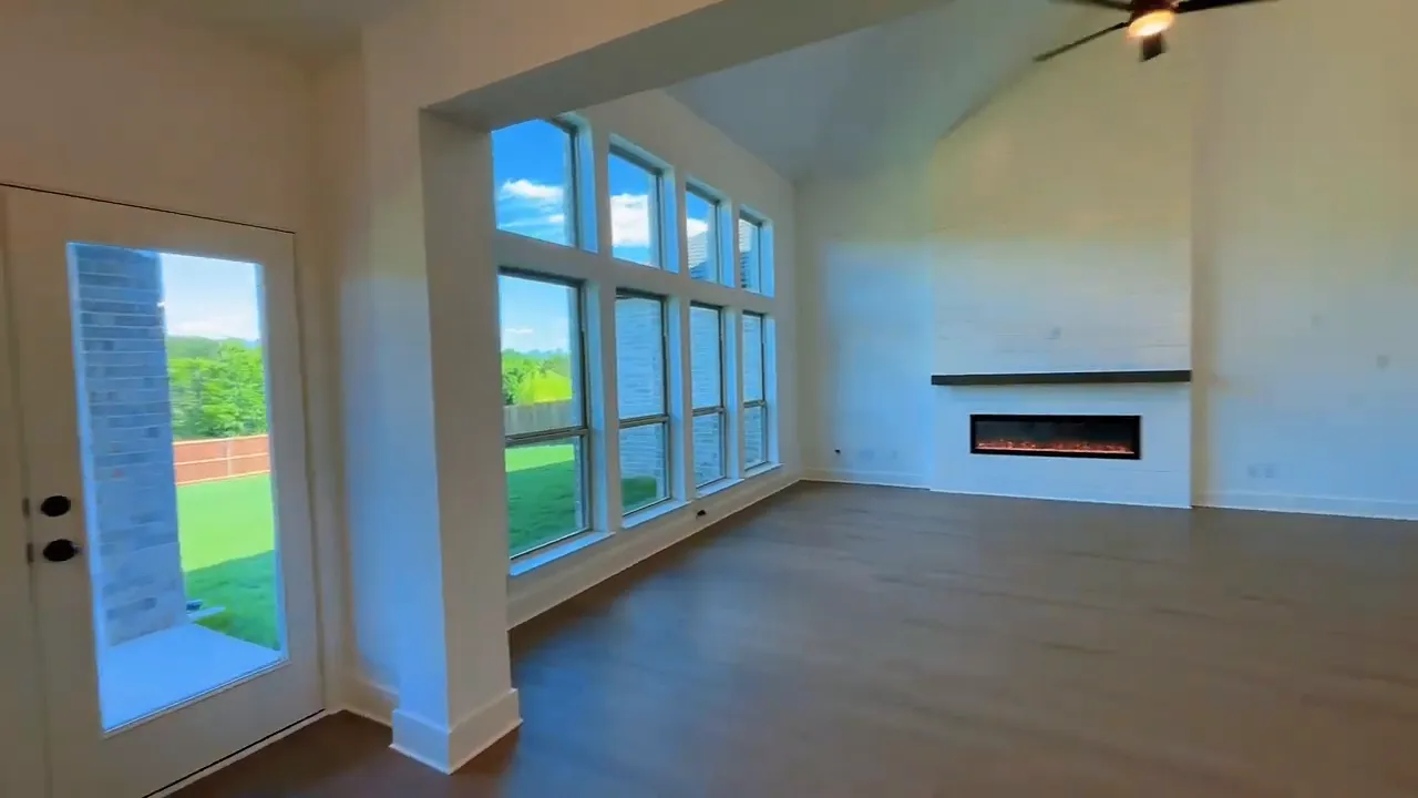 Large living room with tall windows fireplace ceiling fan and staircase