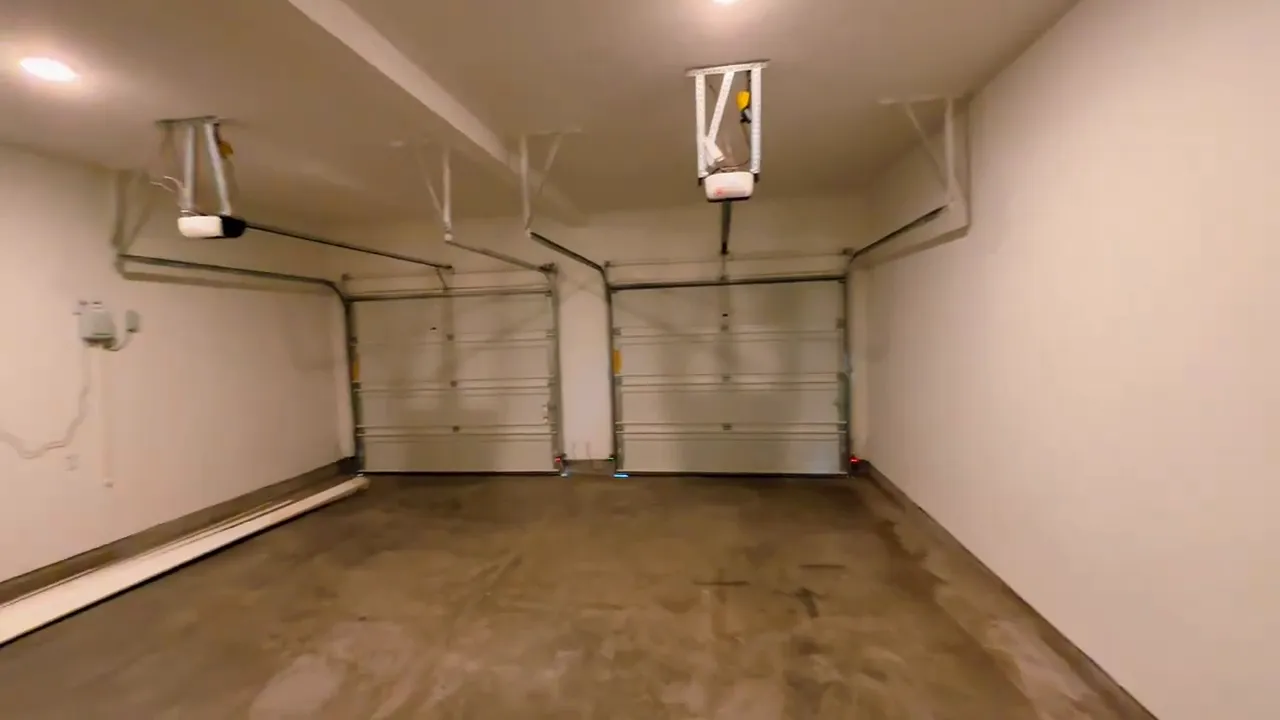 Spacious garage interior with two overhead doors and concrete floor
