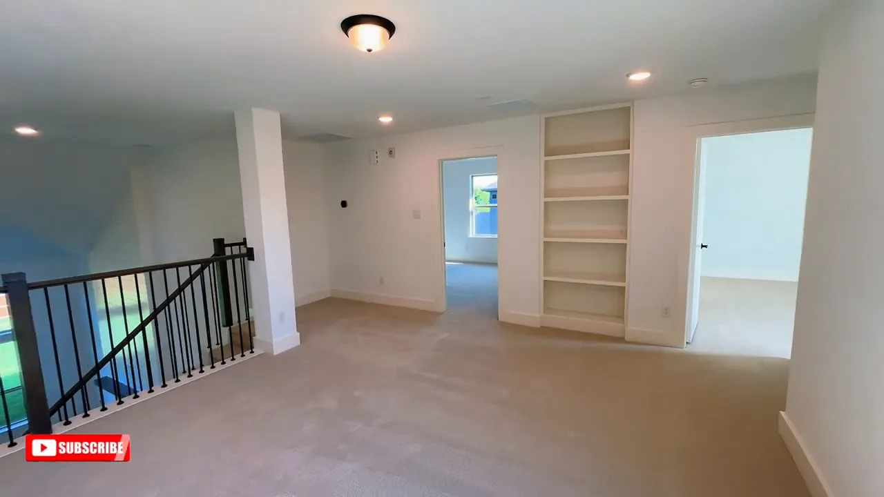 Upstairs game room with railing recessed lights and built in bookshelves