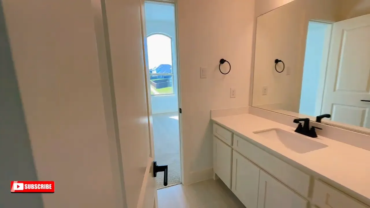 Bathroom vanity with mirror and adjacent doorway between upstairs rooms