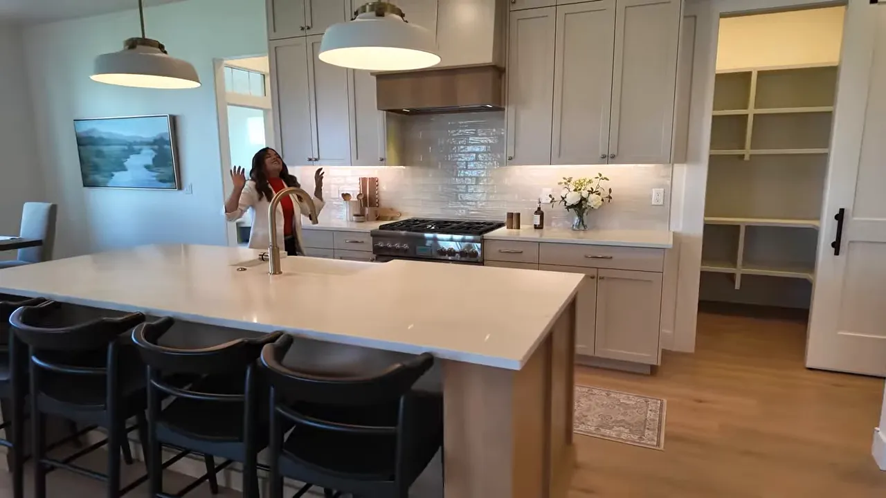 Large kitchen island with pendant lights range and built-in pantry
