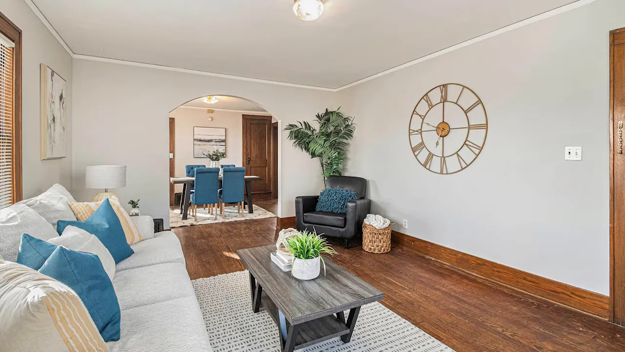Staged living room with neutral decor, blue pillows and hardwood floors in an Omaha home