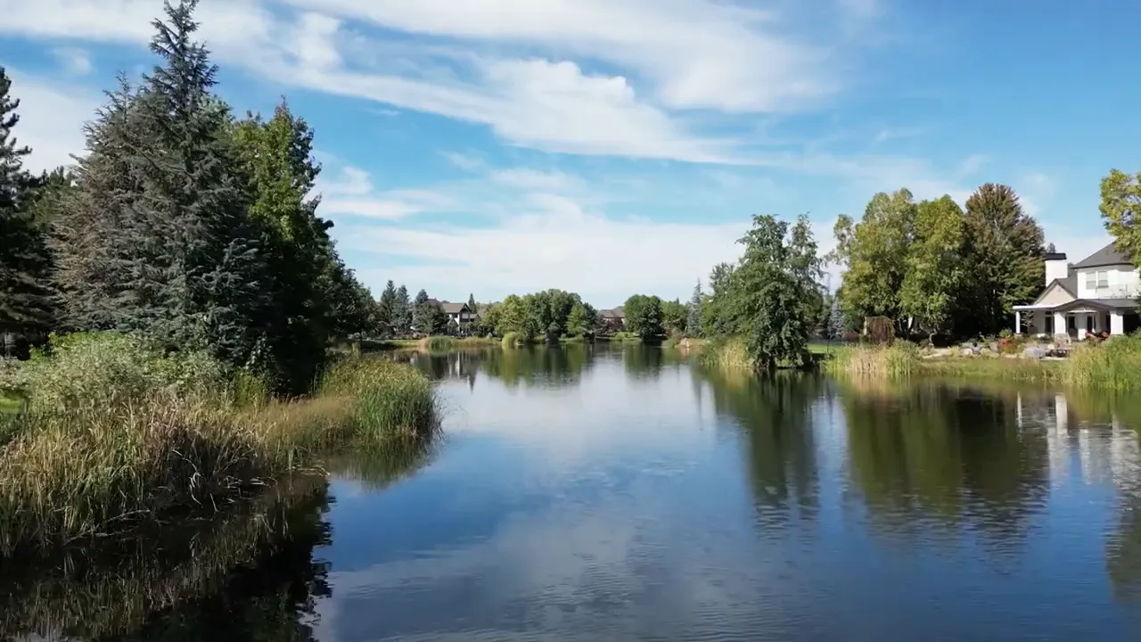Calm neighborhood pond with trees and homes around the shoreline